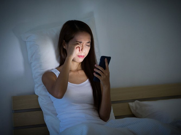 Việc sử dụng điện thoại trong bóng tối trước khi ngủ khiến thị lực giảm, mỏi mắt, khô mắt. (Ảnh: Internet)